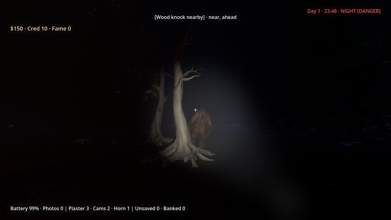 A large hairy figure half hidden behind a pale tree trunk in a flashlight beam at night